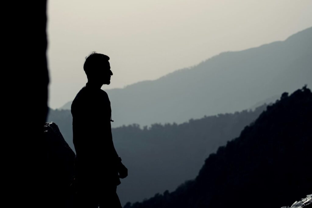 Silhouette of a man standing on top of the mountain.