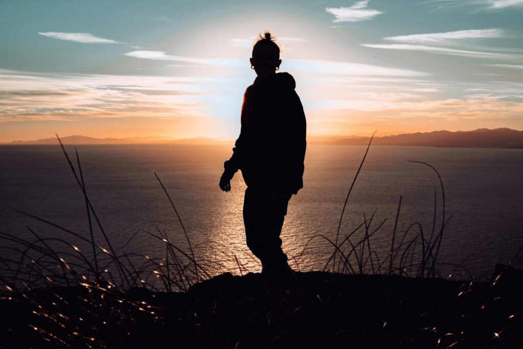 Photo of a person’s silhouette standing on the hill, embracing change for self-discovery. 